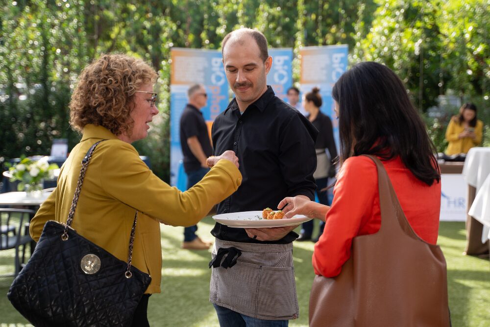Waiter presenting a tray of appetizers to attendees of an outdoor reception